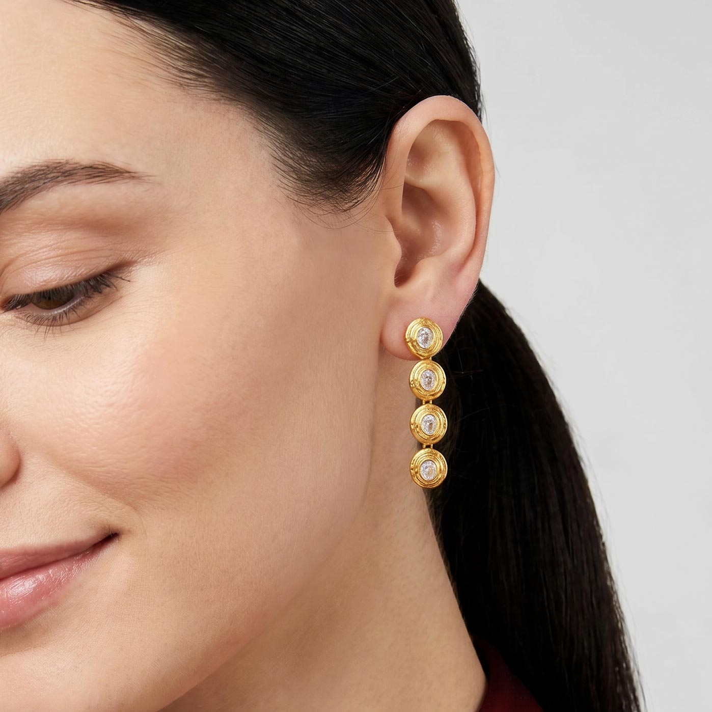 Close-up of a woman wearing gold earrings with a gray background, carousel