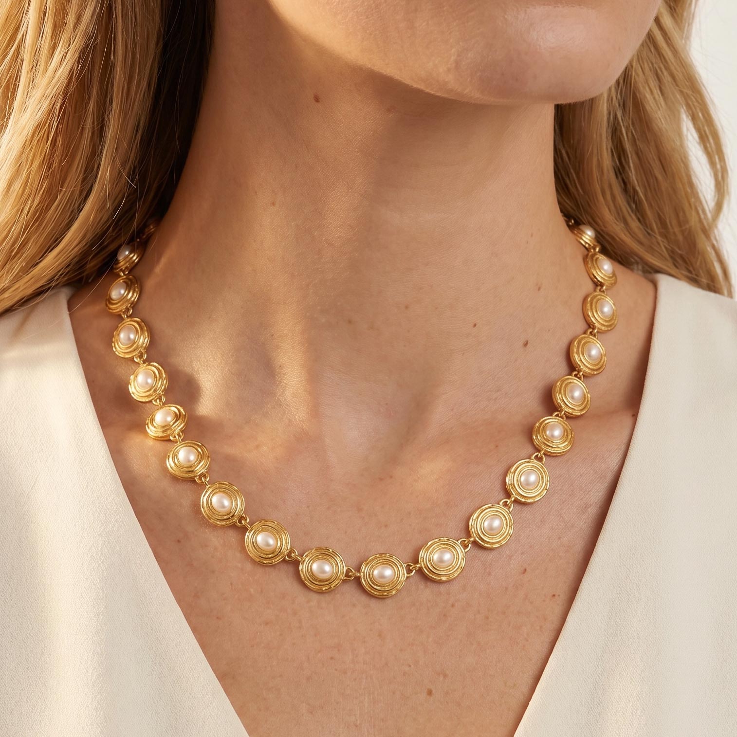 Gold necklace with pearl-like beads worn by a person, carousel