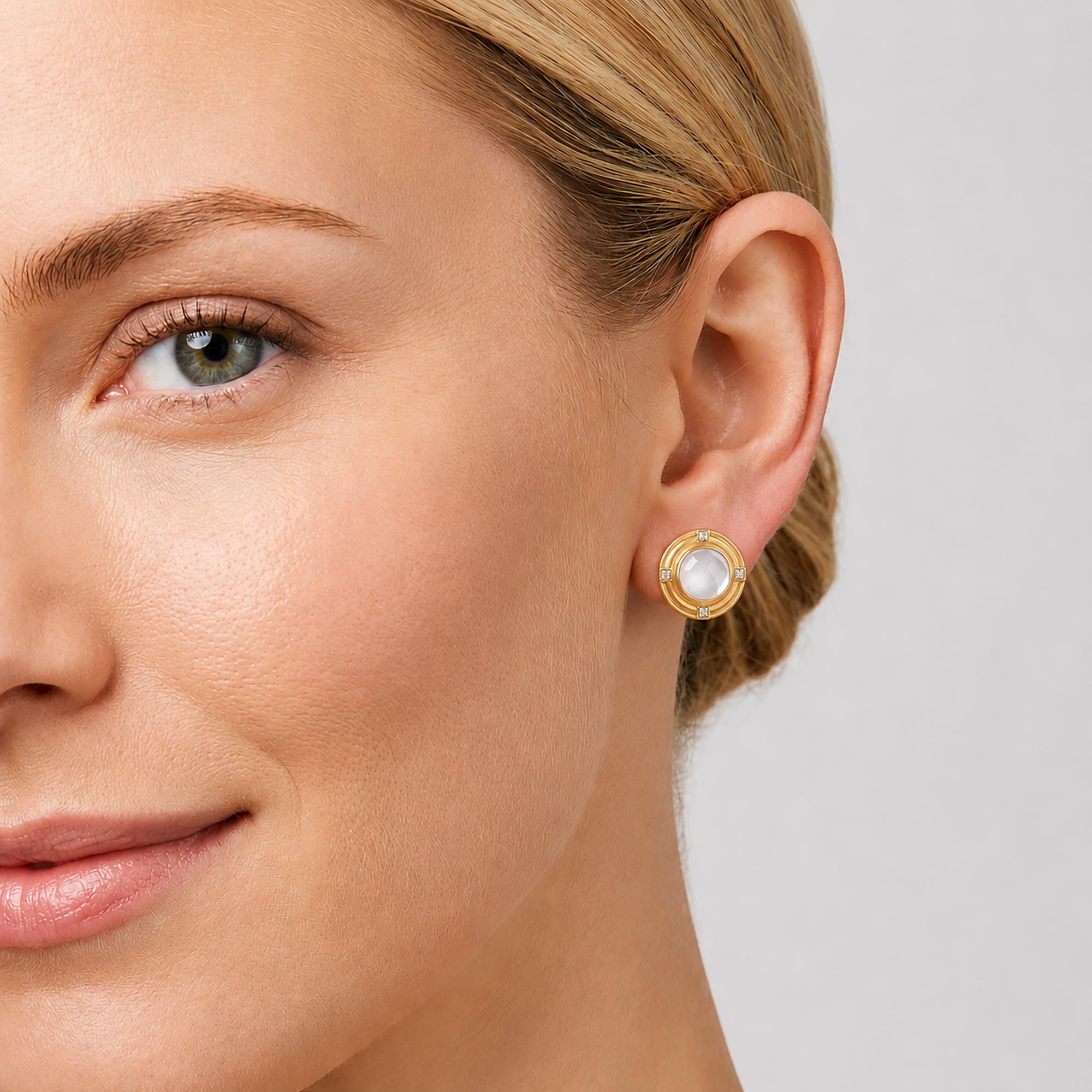 Close-up of a woman wearing gold earrings with a gray background, carousel
